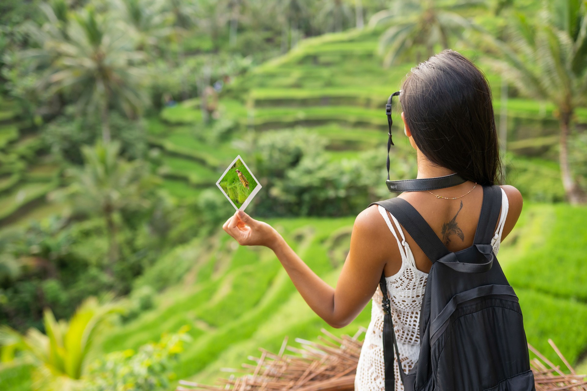 Woman walking at beautiful rice field landscape in Bali and taking pictures