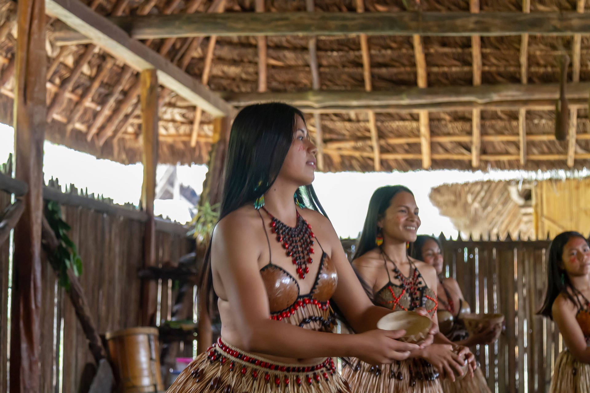 A young beautiful indigenous female portrait, dressed in her traditional attire clothes dancing with her tribu while shooting in her village. Tribu Quichua / Kichwa napuruna.